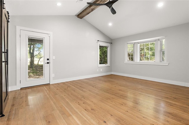 spare room with ceiling fan, a barn door, lofted ceiling with beams, and light hardwood / wood-style flooring