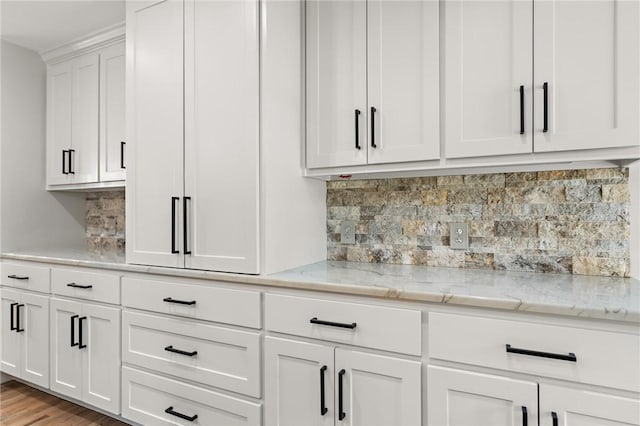 interior space featuring white cabinets, decorative backsplash, light hardwood / wood-style floors, and light stone countertops