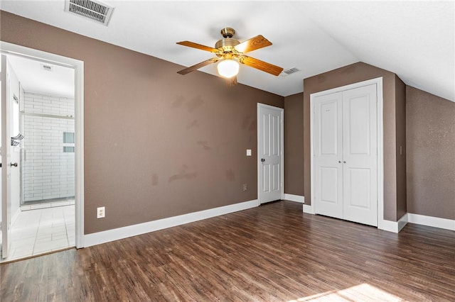 unfurnished bedroom featuring lofted ceiling, connected bathroom, ceiling fan, and dark wood-type flooring