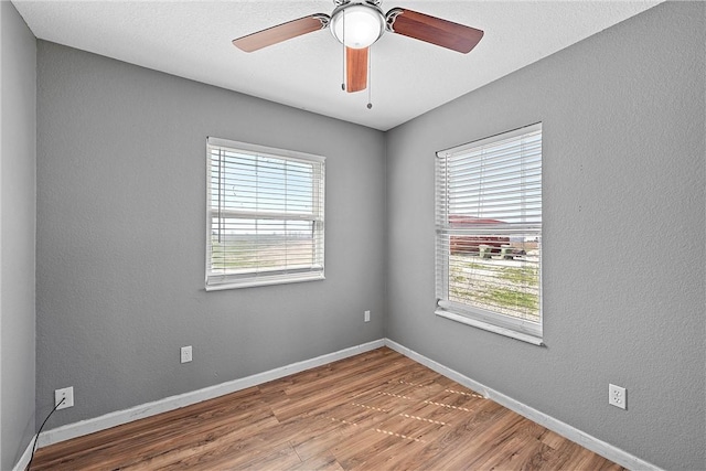 unfurnished room with hardwood / wood-style floors, ceiling fan, and a healthy amount of sunlight