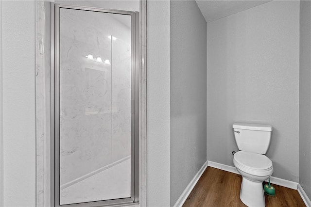 bathroom with hardwood / wood-style floors, toilet, and a shower