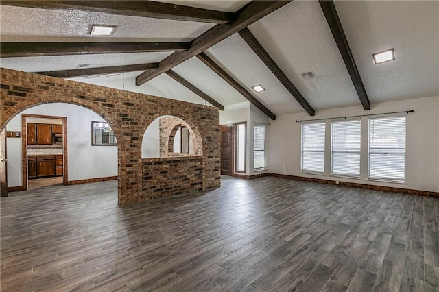 unfurnished living room featuring dark wood-type flooring, lofted ceiling with beams, and a textured ceiling