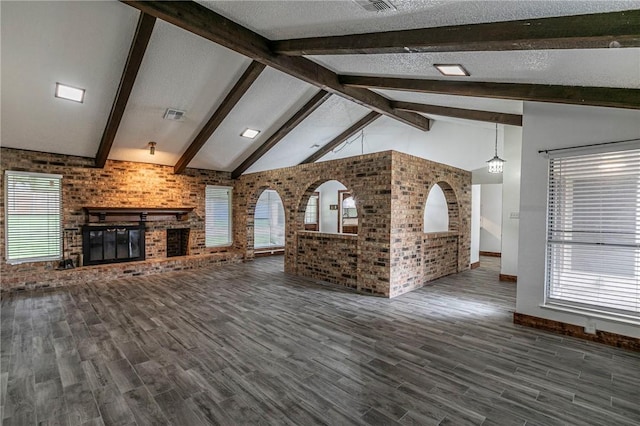 unfurnished living room featuring hardwood / wood-style flooring, brick wall, a fireplace, and vaulted ceiling with beams