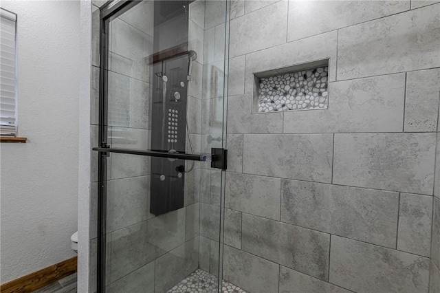 bathroom featuring toilet and a shower with shower door