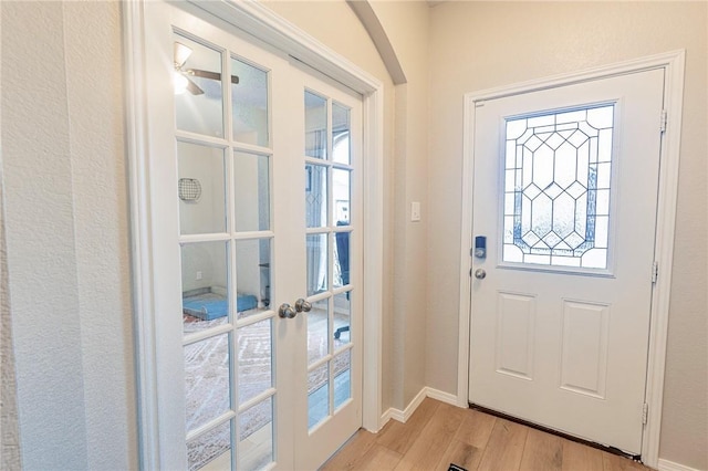 entryway featuring light wood-style floors, baseboards, and french doors