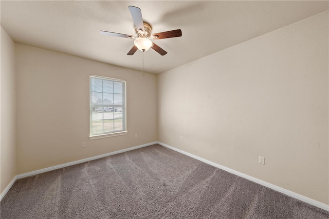 carpeted spare room with a ceiling fan and baseboards