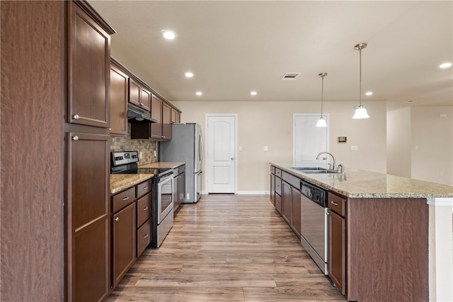 kitchen with visible vents, a kitchen island with sink, a sink, stainless steel appliances, and light wood finished floors