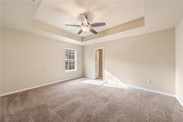 unfurnished room with a raised ceiling, a ceiling fan, baseboards, and light carpet