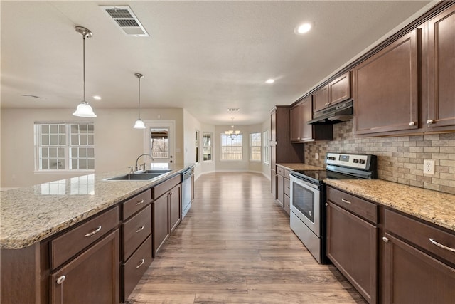 kitchen featuring visible vents, under cabinet range hood, decorative backsplash, appliances with stainless steel finishes, and a sink