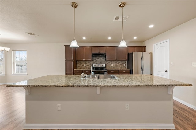 kitchen with tasteful backsplash, visible vents, a kitchen breakfast bar, and stainless steel appliances