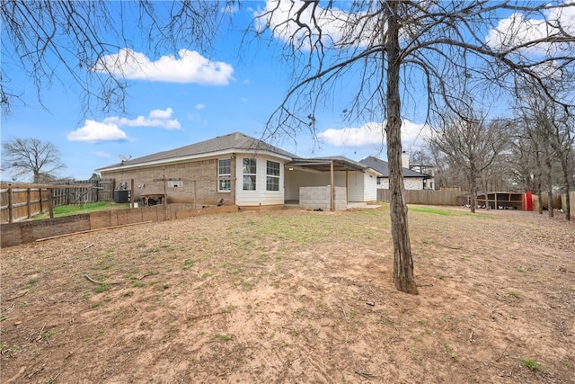 back of house featuring brick siding, central AC, and a fenced backyard