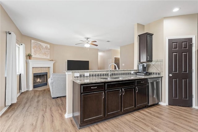 kitchen with sink, decorative backsplash, stainless steel dishwasher, dark brown cabinets, and light hardwood / wood-style flooring