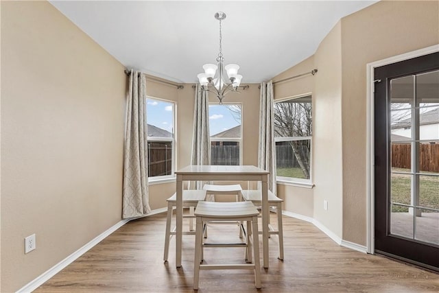 unfurnished dining area featuring a chandelier, vaulted ceiling, and light hardwood / wood-style flooring