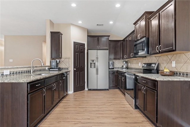 kitchen featuring light hardwood / wood-style flooring, appliances with stainless steel finishes, dark brown cabinets, light stone counters, and vaulted ceiling