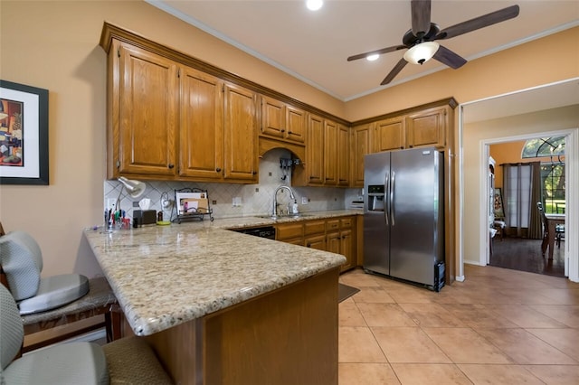 kitchen with crown molding, kitchen peninsula, ceiling fan, stainless steel fridge with ice dispenser, and a breakfast bar area