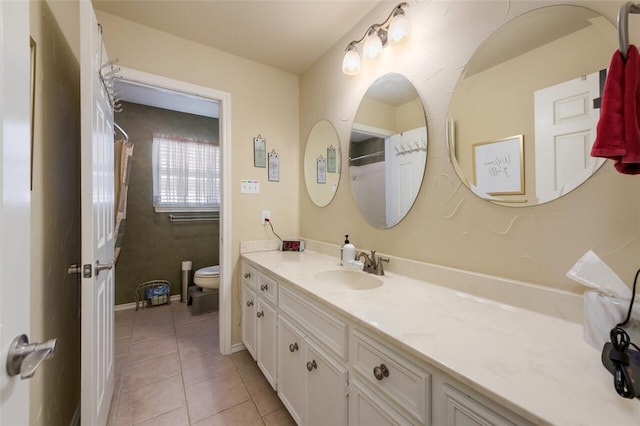 bathroom with toilet, vanity, and tile patterned floors