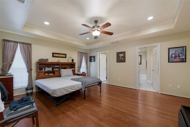 bedroom featuring a raised ceiling, ceiling fan, hardwood / wood-style floors, and ensuite bathroom