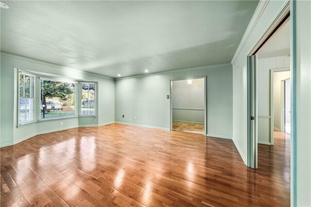 unfurnished room featuring wood-type flooring and ornamental molding