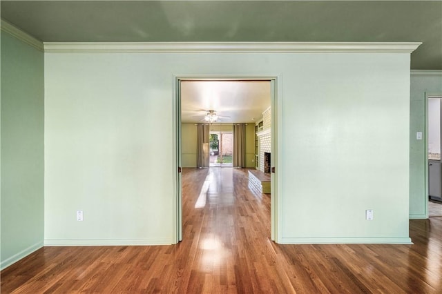 empty room featuring a fireplace, hardwood / wood-style flooring, and crown molding