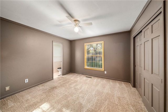 unfurnished bedroom featuring ensuite bath, ceiling fan, crown molding, and light colored carpet