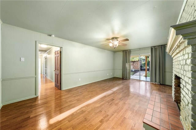 unfurnished living room featuring hardwood / wood-style flooring, ceiling fan, and a brick fireplace