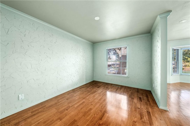 unfurnished room featuring plenty of natural light, hardwood / wood-style floors, and ornamental molding