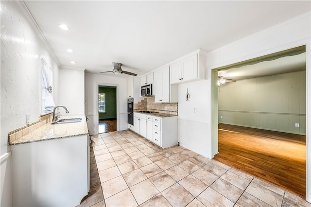 kitchen with white cabinetry, sink, stainless steel appliances, light stone counters, and light wood-type flooring