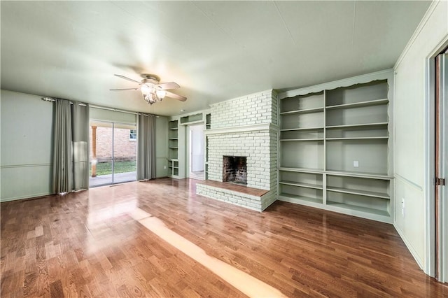 unfurnished living room with a fireplace, hardwood / wood-style floors, ceiling fan, and built in shelves