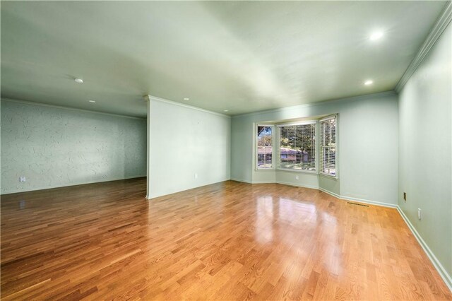 empty room featuring light wood-type flooring and ornamental molding