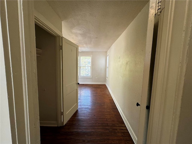 corridor with dark hardwood / wood-style flooring and a textured ceiling