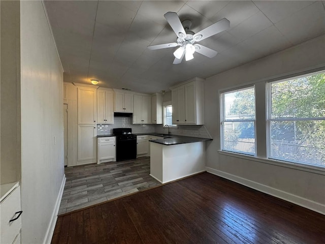 kitchen with black stove, dark hardwood / wood-style floors, white cabinetry, and sink