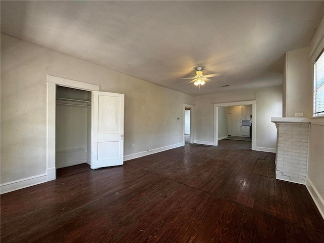 unfurnished living room featuring ceiling fan, a fireplace, and dark wood-type flooring