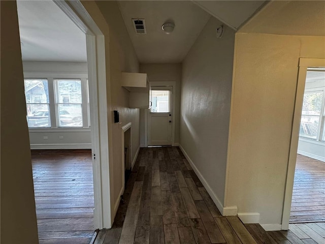 hall with a healthy amount of sunlight and dark wood-type flooring