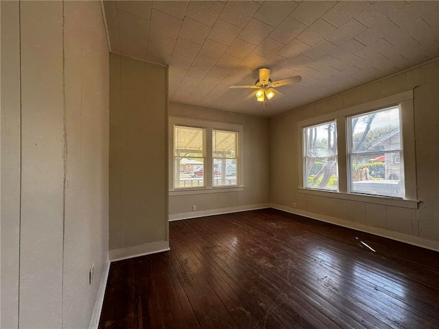 empty room with plenty of natural light, dark wood-type flooring, and ceiling fan