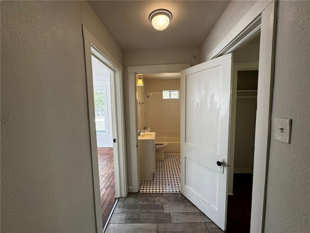 hall with a textured ceiling and dark hardwood / wood-style floors