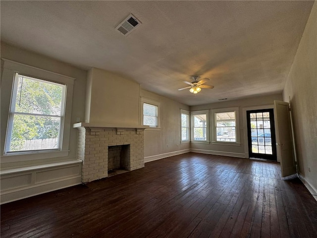 unfurnished living room featuring dark hardwood / wood-style floors, a brick fireplace, a wealth of natural light, and ceiling fan