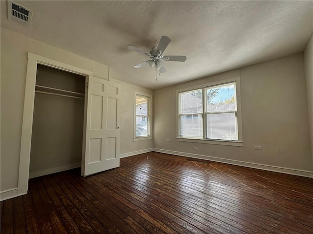 unfurnished bedroom with a textured ceiling, a closet, dark hardwood / wood-style floors, and ceiling fan