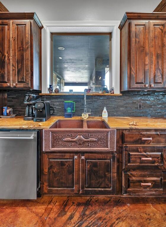 kitchen featuring decorative backsplash, butcher block countertops, stainless steel dishwasher, and sink