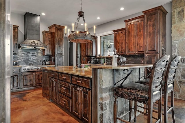 kitchen featuring a breakfast bar, decorative backsplash, stainless steel gas cooktop, and wall chimney range hood