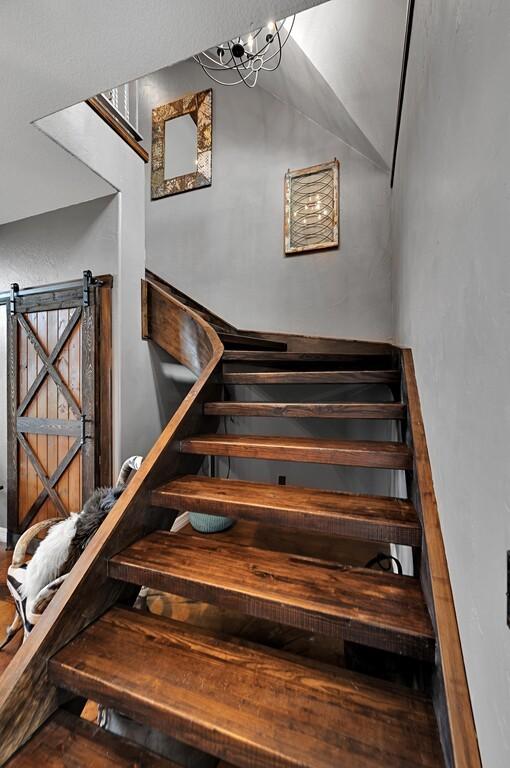 stairs with a barn door and a chandelier