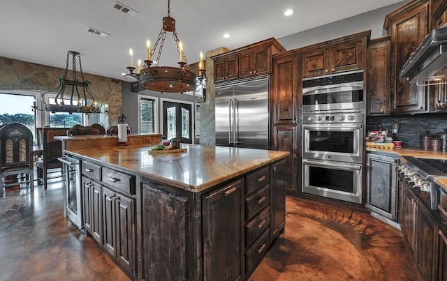 kitchen featuring a wealth of natural light, a kitchen island, decorative light fixtures, and appliances with stainless steel finishes