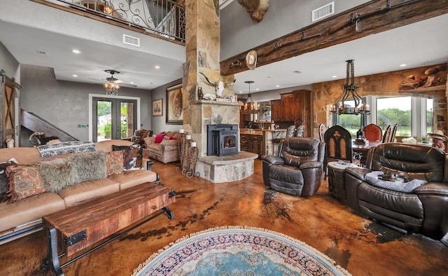 living room with french doors, ceiling fan with notable chandelier, a wood stove, and a healthy amount of sunlight