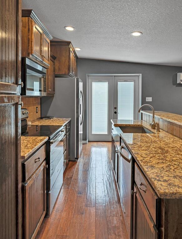 kitchen with appliances with stainless steel finishes, a textured ceiling, dark hardwood / wood-style floors, and sink