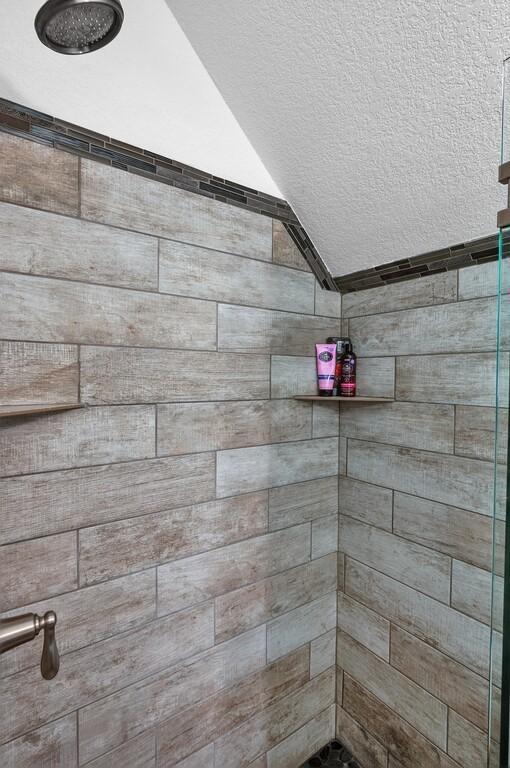 bathroom featuring a shower, lofted ceiling, and a textured ceiling