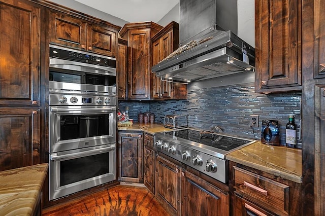 kitchen featuring decorative backsplash, dark brown cabinets, stainless steel appliances, and wall chimney range hood