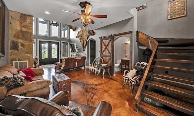 living room featuring french doors, concrete floors, ceiling fan, and a barn door