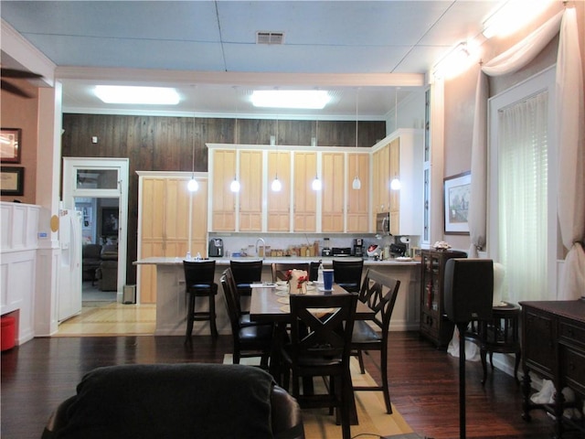 dining space with hardwood / wood-style floors, wood walls, and sink