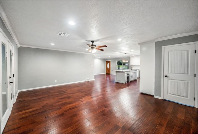 unfurnished living room with a textured ceiling, dark hardwood / wood-style flooring, ceiling fan, and ornamental molding