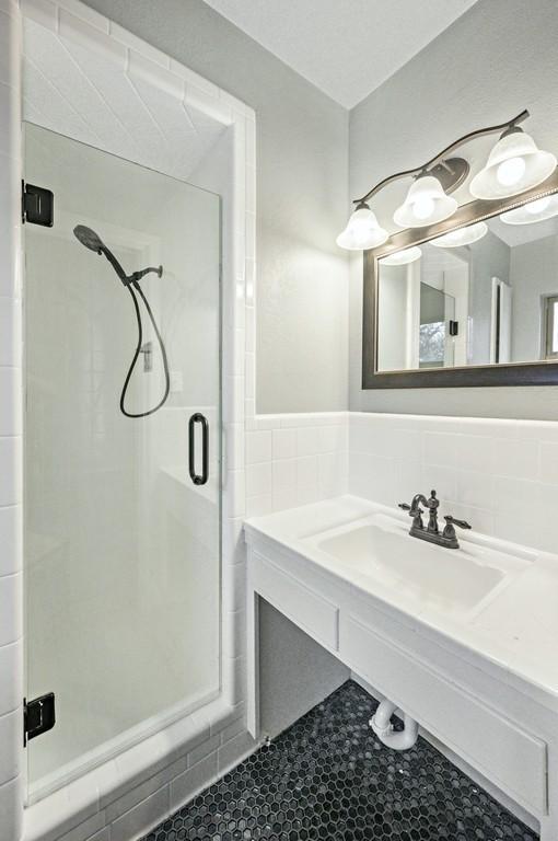 bathroom featuring tile patterned floors, a shower with shower door, and sink