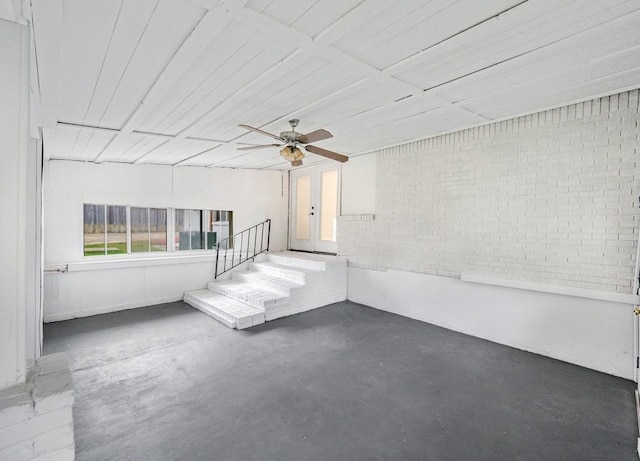 unfurnished room with ceiling fan and brick wall